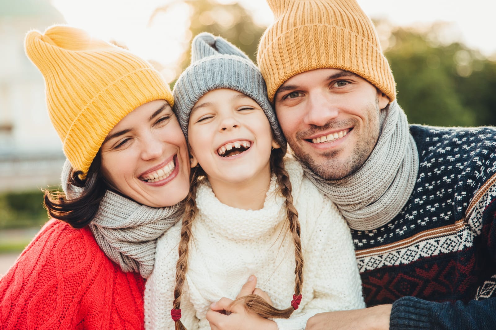 A smiling mother, father and daughter in knitted winter hats and scarves